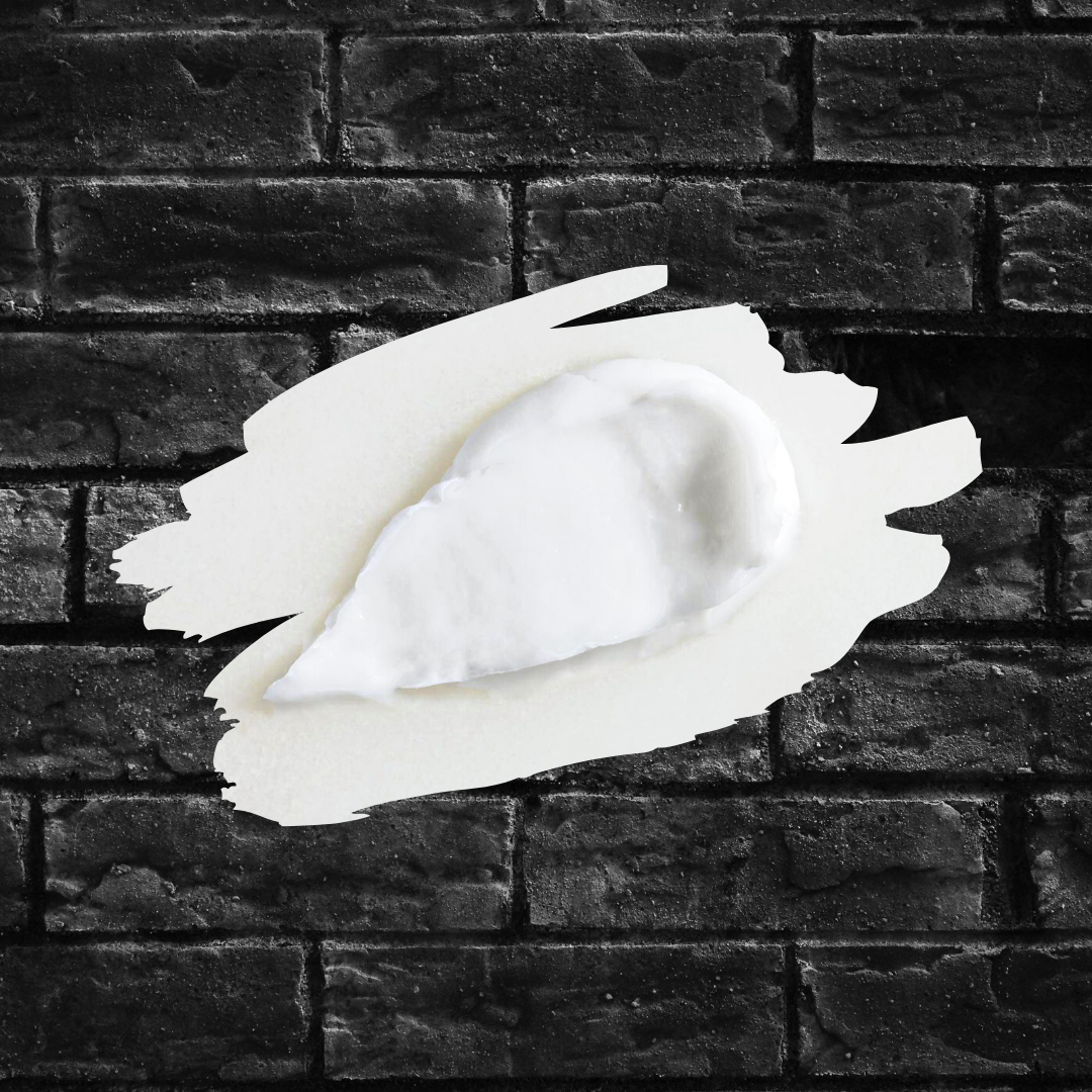White texture shot of a schmear of Moisture Recovery Cream set against a black brick wall. Text reads: Ingredient Spotlight on Ceramides. 